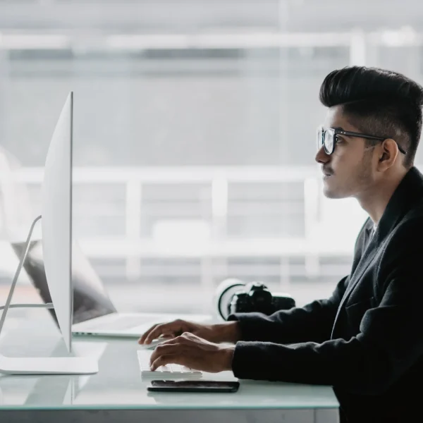 confident-photographer-cheerful-young-man-holding-digital-camera-smiling-while-sitting-his-working-place